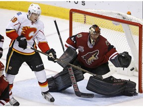 Arizona Coyotes goalie Mike Smith, right, makes a save on a redirect from Calgary Flames left wing Matthew Tkachuk (19) during the second period of an NHL hockey game Thursday, Dec. 8, 2016, in Glendale, Ariz.