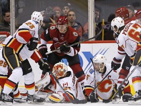 Arizona Coyotes left wing Max Domi (16) gets the puck past Calgary Flames goalie Chad Johnson, bottom left, for a goal as Flames' defenseman Deryk Engelland (29), center Sean Monahan (23), defenseman Mark Giordano (5), right wing Michael Frolik (67), and Coyotes' center Christian Dvorak (18) and right wing Shane Doan, right, all look for the puck during the first period of an NHL hockey game Thursday, Dec. 8, 2016, in Glendale, Ariz.
