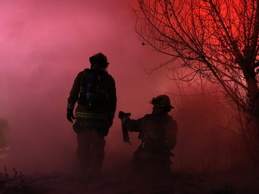 Calgary firefighters work in dense smoke while extinguishing a fire in a mobile home at the Midfield Mobile Home Park on Wednesday evening December 7, 2016.