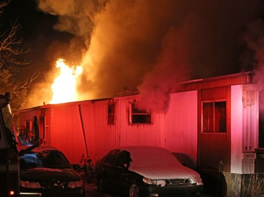 Flames leap from the back of a mobile home as Calgary firefighters extinguish a fire in the structure at the Midfield Mobile Home Park on Wednesday evening December 7, 2016.
