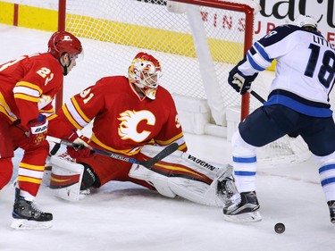 The Calgary Flames goaltender Chad Johnson stops this scoring chance by Winnipeg Jets forward Bryan Little during NHL action at the Scotiabank Saddledome in Calgary on Saturday December 10, 2016.
