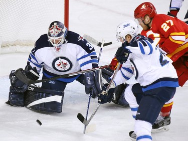 Calgary Flames Dougie Hamilton tries to get the puck past Winnipeg Jets goaltender Michael Hutchinson and winger Patrik Laine during NHL action at the Scotiabank Saddledome in Calgary on Saturday December 10, 2016.
