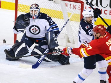 The Calgary Flames Lance Bouma attempt to deflect a puck towards Winnipeg Jets goaltender Michael Hutchinson during the second period of NHL action at the Scotiabank Saddledome in Calgary on Saturday December 10, 2016.