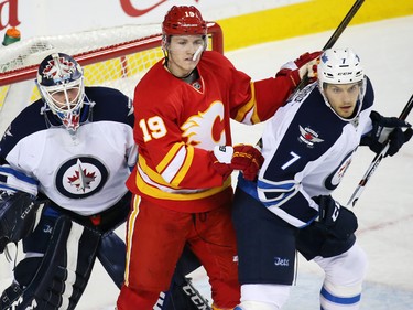 Calgary Flames forward Matthew Tkachuk fights for position between Winnipeg Jets goaltender Michael Hutchinson and defensemen Ben Chiarot during the second period of NHL action at the Scotiabank Saddledome in Calgary on Saturday December 10, 2016.