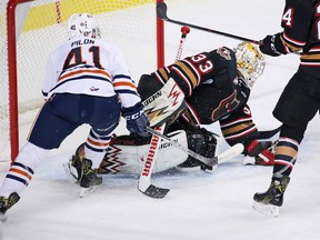 Calgary Hitmen goaltender Kyle Dumba covers the puck as the Kamloops Blazers' Garrett Pilon reaches in during WHL action at the Scotiabank Saddledome in Calgary on Sunday December 11, 2016.