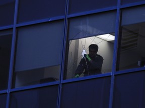 A man removes loose glass from an office building in the 900 block of 6th avenue S.W. after two windows in the building were damaged on Thursday December 22, 2016. The Calgary Fire Department was investigating to find out what damaged the windows