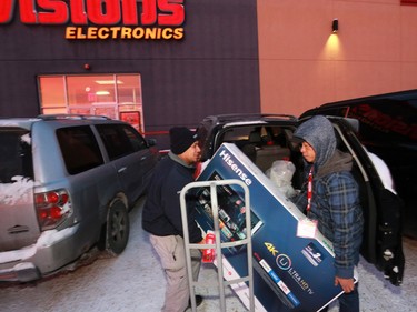Edgar Guevarra, left, get some help loading a new TV from Visions after a Boxing Day sale on December 26, 2016.