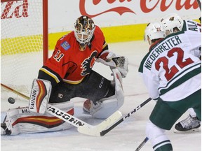 Calgary Flames goalie Chad Johnson steers the puck away as Minnesota Wild Nino Niederreiter and Erik Haula move in in NHL hockey action at the Scotiabank Saddledome in Calgary, Alta. on Friday December 2, 2016.