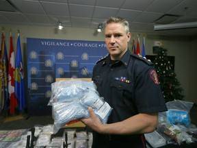 Calgary Police Acting Insp Mark Hatchette of the Strategic Enforcement Unit displays on December 29, 2016 a large amount of drugs, cash and various weapons following a one month operation.