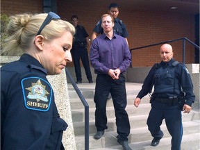 Travis Vader is escorted out of court following his first court appearance for the deaths of Lyle and Marie McCann.