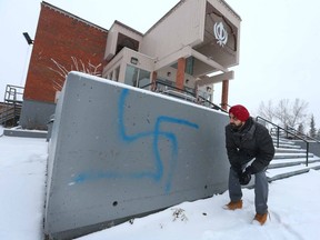 Harpeet Singh Gill, a volunteer at the Sikh Society Temple, examines graffitti on the ouside of the building located on 81 St SW on Friday December 23, 2016 in Calgary, Alta. The spray paint was discovered a day or so ago and is similar to both a swastika and a Hindu symbol. Jim Wells//Postmedia