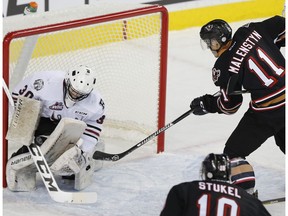 Calgary Hitmen Beck Malenstyn tries to sneak on passed Red Deer Rebels goalie Lasse Petersen during game action in Calgary, on December 9, 2016.