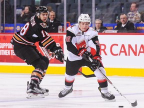 Murphy Stratton #18 of the Calgary Hitmen chases Dakota Odgers #36 of the Moose Jaw Warriors during a WHL game at Scotiabank Saddledome on November 25, 2016.