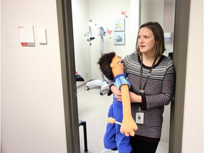 Emily Synnott, Child Life Specialist with the Sheldon Kennedy Child Advocacy Centre, holds a doll by one of the centre's medical examine rooms. The doll is used to help children understand about medical examines. The centre's goal is to make it easier for child victims to share information and begin the healing process.