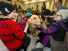 Students Lisa Judnic, left, and Jasmine Spearing hang out with Hawaii, a Pacific Assistance Dog Society pooch in training, at Bow Valley College.