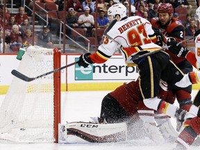 Calgary Flames' Sam Bennett (93) gets sent flying into the air by Arizona Coyotes' Nicklas Grossmann (2), of Sweden, but not before he sends the puck past Coyotes goalie Louis Domingue, bottom left, for a goal as Flames' Joe Colborne (8) watches during the first period of an NHL hockey game, Monday, March 28, 2016, in Glendale, Ariz.