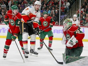 Calgary Flames defenseman TJ Brodie (7) goes airborne as Minnesota Wild goalie Devan Dubnyk (40) makes a save during the second period of an NHL hockey game, Tuesday, Nov. 15, 2016, in St. Paul, Minn. Wild defenseman Ryan Suter (20) is at left. Calgary won 1-0.