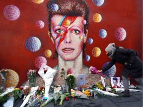 FILE PHOTO: LONDON, ENGLAND - JANUARY 11:  A woman leaves flowers beneath a mural of David Bowie in Brixton on January 11, 2016 in London, England. British music and fashion icon David Bowie died earlier today at the age of 69 after a battle with cancer.