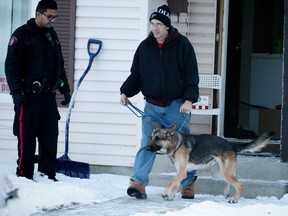A man walks a German Shepherd out of a house after a serious dog bite involving a four-year-old boy in the city's northeast on Castleridge Way N.E, on Tuesday January 3, 2017.