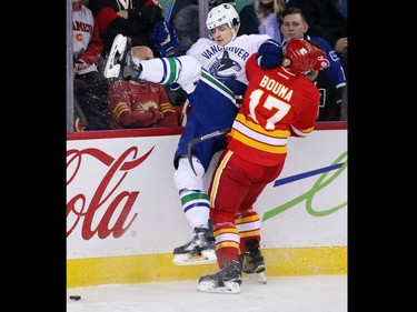 The Calgary Flames' Lance Bouma checks Vancouver Canucks defenceman Luca Sbisa into the boards during NHL action at the Scotiabank Saddledome in Calgary on Saturday January 7, 2017.