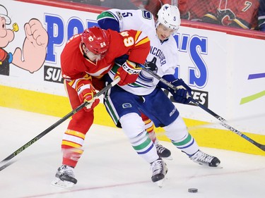 The Calgary Flames' Garnet Hathaway and the Vancouver Canucks' Luca Sbisa battle for control during NHL action at the Scotiabank Saddledome in Calgary on Saturday January 7, 2017.