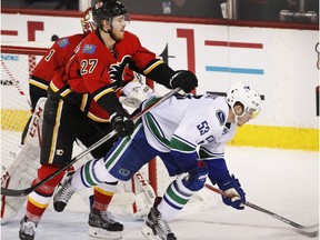 Vancouver Canucks' Bo Horvat, right, is moved away from the Calgary net by Calgary Flames' Dougie Hamilton during third period NHL action in Calgary, Friday, Dec. 23, 2016.