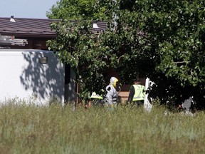 Police in hazmat suits investigate the farm of the family of Douglas Garland on July 9, 2014 north of Airdrie.