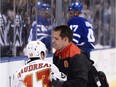 Calgary Flames left wing Johnny Gaudreau is attended to by a trainer as Toronto Maple Leafs centre Leo Komarov enters the penalty box in Toronto on Monday, Jan. 23, 2017. (The Canadian Press)