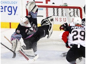 Calgary Hitmen Trevor Martin blocks a shot from Prince George Cougars Jesse Gabrielle, right, in WHL action at the Scotiabank Saddledome in Calgary, Alberta, on Saturday, January 14, 2017.