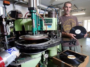 Dean Reid of Canada Boy Vinyl holds up a hot of the press album alongside his automatic vinyl record press Monday August 15, 2016. Reid's business is Canada's lone vinyl pressing plant. (Ted Rhodes/Postmedia)