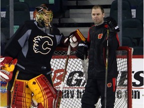 Calgary Flames goalie coach Jordan Sigalet with goalie Jonas Hiller on the ice during practice at the Scotiabank Saddledome in Calgary on January 4, 2016.