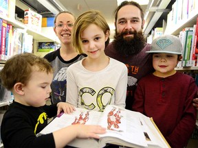 Colby Deremiens looks up from behind a book of science and mathematics with her parents Kara Deremiens and Jason Milne and brothers Tiberius and Xavier Milne looking on January 27. Colby's parents are hopeful she will be given a chance to take on a science-based education. RYAN MCLEOD FOR POSTMEDIA CALGARY