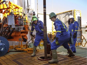 Trainees Dan Brook and Bradley Williams are directed by instructor Clint Dyck while training to lay down drill pipe on a rig floor, at Precision Drilling in Nisku, Alberta.