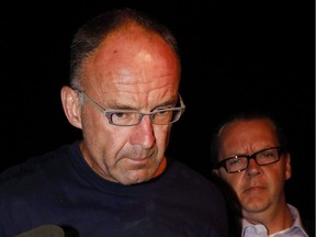 Douglas Garland is escorted into a police station in Calgary on July 14, 2014.
