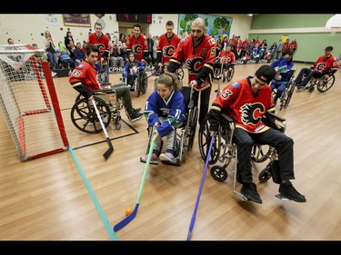 Calgary Flames captain Mark Giordano helps Jessica of the Townsend Tigers to get past Johnny Gaudreau of the Flames as Sean Monahan mans the net during an annual wheelchair floor hockey game between the Townsend Tigers and the Flames at the Alberta Children's Hospital in Calgary, Alta., on Tuesday, Jan. 31, 2017. The Townsend Tigers, made up of kids who attend Dr. Gordon Townsend School at the hospital, beat the Flames for the 36th year in a row, this year by a 15-0 score. Lyle Aspinall/Postmedia Network