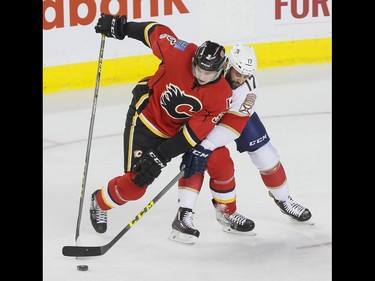 Jyrki Jokipakka of the Calgary Flames battles for a puck with Derek MacKenzie of the Florida Panthers during NHL action in Calgary, Alta., on Tuesday, Jan. 17, 2017. Lyle Aspinall/Postmedia Network