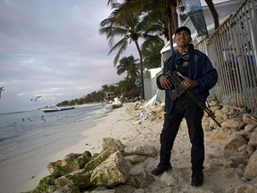A municipal police officer stands guard on the beach in front of the Blue Parrot club, a day after a deadly early morning shooting, in Playa del Carmen, Mexico, Tuesday, Jan. 17, 2017.