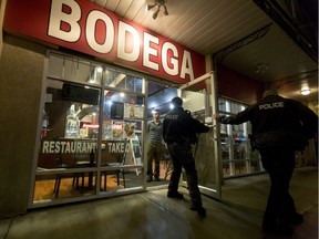 Police walk out of the Bodega restaurant in the Kensington area of Calgary, Alta., on Wednesday, Jan. 18, 2017. They were responding to reports of gunfire from across the street. Lyle Aspinall/Postmedia Network