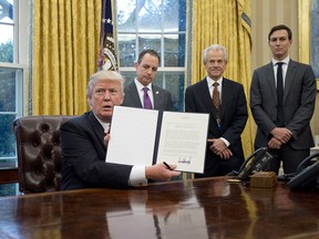 U.S. President Donald Trump shows the Executive Order withdrawing the US from the Trans-Pacific Partnership (TPP) after signing it in the Oval Office of the White House in Washington, DC on Monday, January 23, 2017.