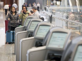 Travellers stand amid a lineup of the existing ticket kiosks inside the international terminal at Calgary International Airport. New kiosks are expected to reduce wait times by 50 per cent.