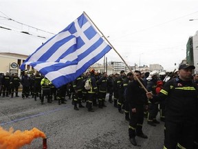 A firefighter holds a Greek flag during a protest in central Athens, on Wednesday, Feb. 8, 2017. Hundreds of firefighters in uniform have taken to the streets of the Greek capital to protest hiring conditions. (AP Photo/Thanassis Stavrakis)