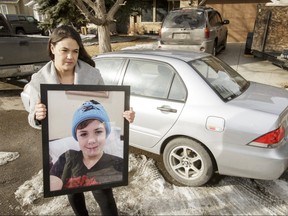 Elissa Carpenter holds a photo of her late son Evan, 14, near her car in Calgary, Alta., on Monday, Feb. 20, 2017. Precious items relating to Evan, who died from a brain aneurysm one month earlier, were recently stolen from her car; Carpenter is imploring the thief to return the items. Lyle Aspinall/Postmedia Network