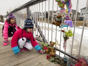 Classmates of a drowned boy pay their respects at a memorial of stuffed toys and flowers on a bridge above icy water in Airdrie, Alta., north of Calgary, on Tuesday, Feb. 21, 2017. A six-year-old boy died there the day before after falling through ice. Lyle Aspinall/Postmedia Network