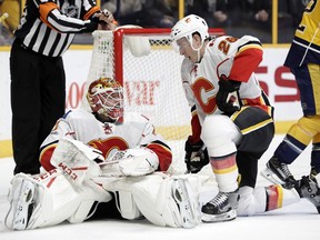 Calgary Flames goalie Brian Elliott (1) and right wing Michael Stone (26) get up off the ice after stopping the puck during the second period of the team's NHL hockey game against the Nashville Predators on Tuesday, Feb. 21, 2017, in Nashville, Tenn.