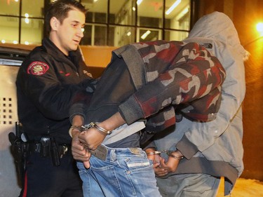 Calgary police escort two men into the Court Services Unit early on Wednesday Feb. 8, 2017. The men were arrested in connection with the September 2016 death of Trevor Lomond.