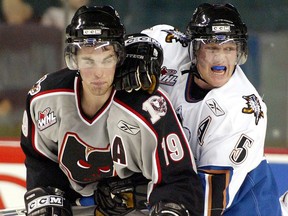 Andrew Ladd (19) of the Hitmen gets a glove in the side of the face from James Cherewyk (5) of Kootenay in front of the net on Oct. 13, 2004.