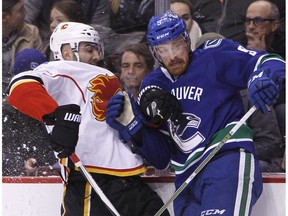 Calgary Flames defenceman Mark Giordano (5) is checked by Vancouver Canucks right wing Jack Skille (9) during first period NHL hockey action in Vancouver on Saturday, February 18, 2017.