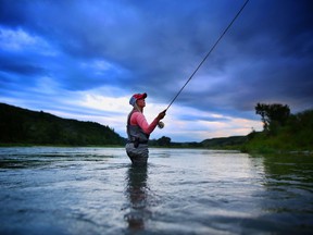 A fisherman enjoys an outing on the Bow River.