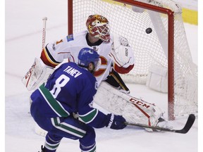 Vancouver Canucks defenceman Christopher Tanev scores the game-winning overtime goal against Calgary Flames goalie Brian Elliott in Vancouver on Saturday, February 18, 2017. (The Canadian Press)