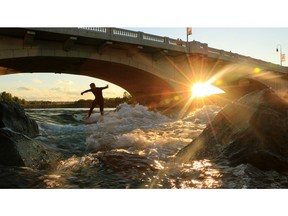 Jacob Kelly Quinlan surfs the wave close to the 10th Street bridge on Bow River on  August 27, 2014.